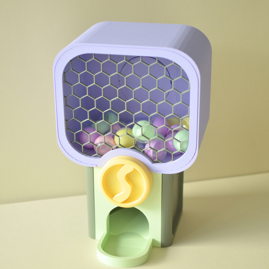 Mini gumball vending machine filled with pastel capsules, lavender top and yellow knob
