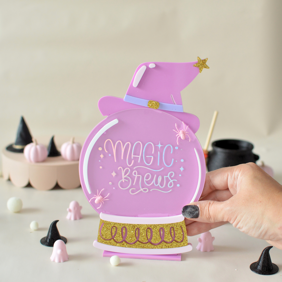 Hand holding the Magic Brews Halloween sign
