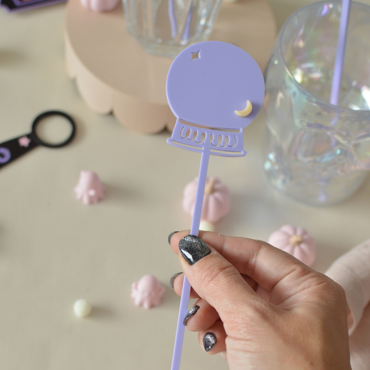 Hand holding a lilac skull drink stirrer