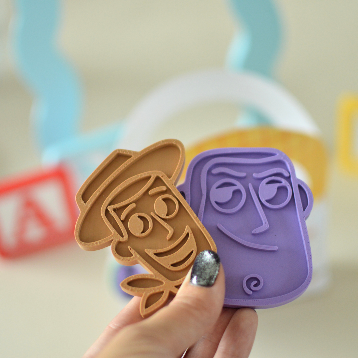 Hand holding two 3D printed play dough cutters