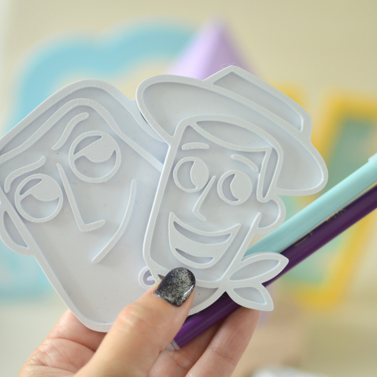 Hand holding two 3D printed colouring plates